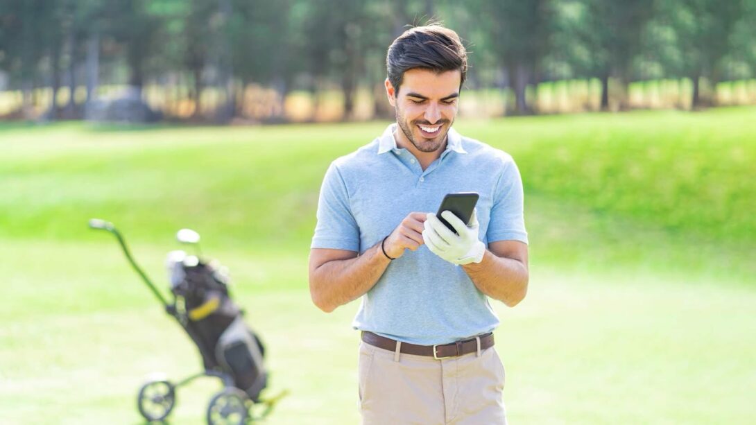 Man looking at phone at golf course