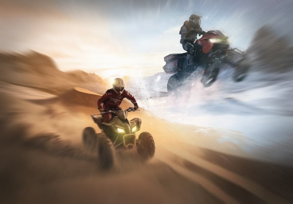 Two racers speed through a desert, one on an ATV, the other on a bike