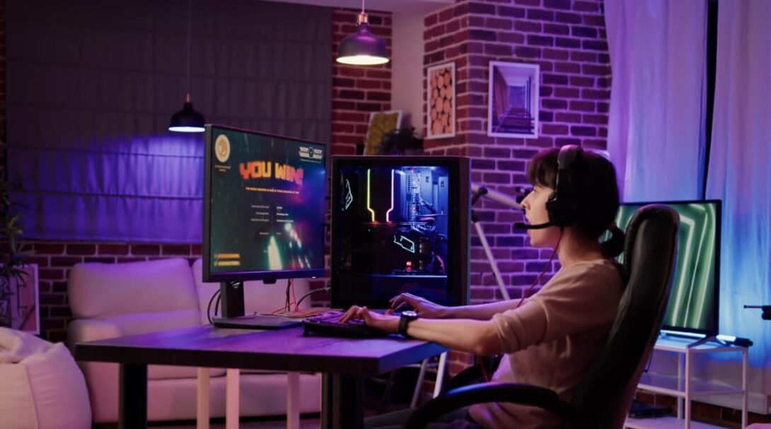 A person gaming in a cozy room with a "You Win" screen display