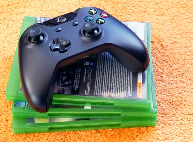 The game console rests on a stack of CD boxes